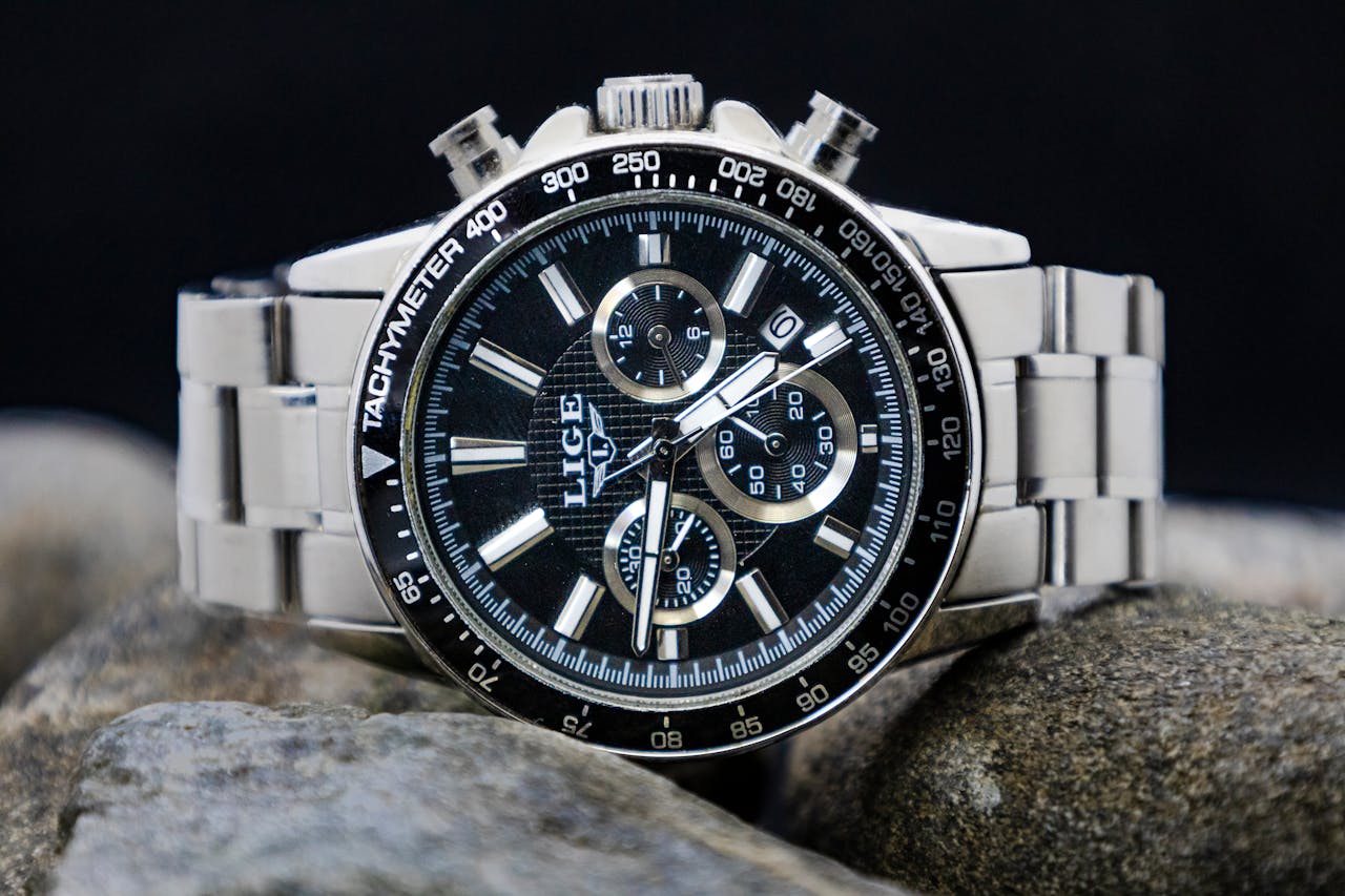 Close-up of a stylish silver wristwatch with multiple dials on rocks.